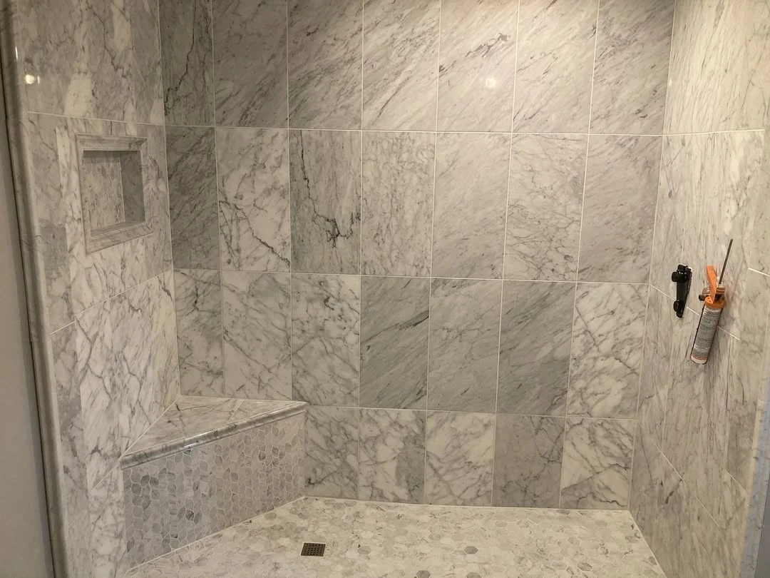 Kristo shower tile project with veined wall tiles, recessed storage, and a built-in bench